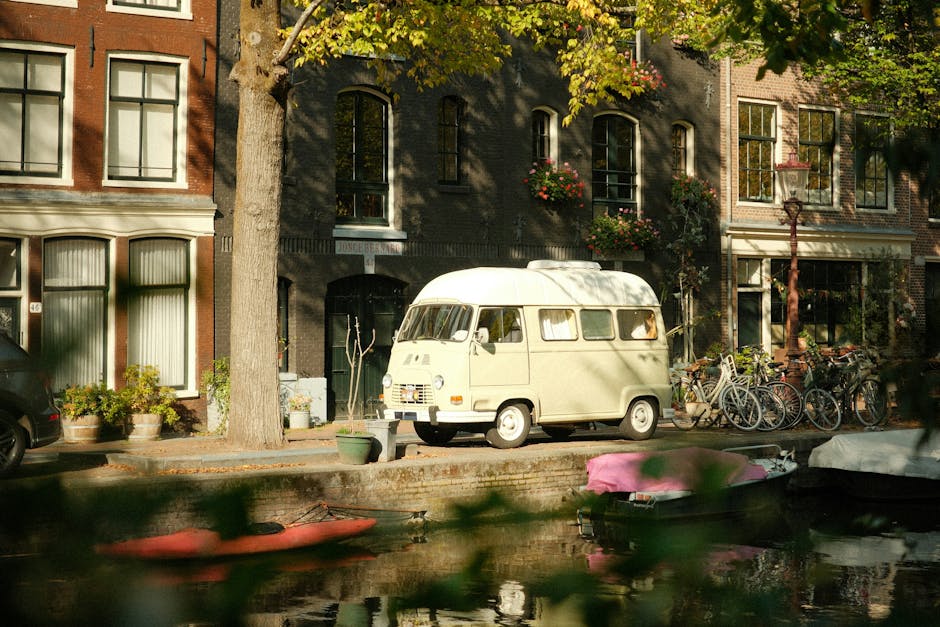 Vintage van parked along a picturesque Amsterdam canal in autumn sunlight.